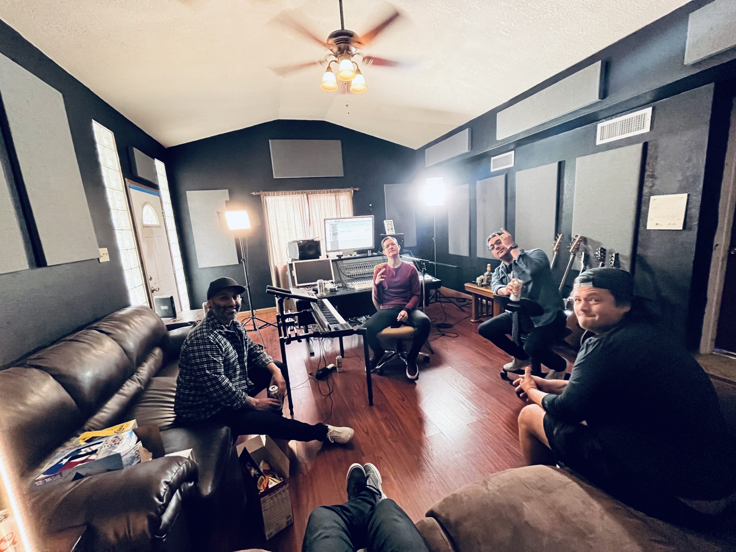 A view of the band Bloom wave looking at the camera and smiling at Let Down Studio with a view of the computer and mixing board.